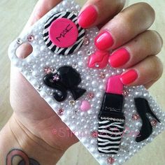 a woman's hand holding a cell phone case with nail polish and accessories on it