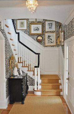 a staircase with pictures on the wall and rug in front of it, along with an entry way leading to another room