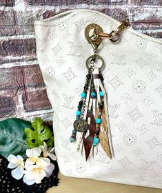 a white purse sitting on top of a wooden table next to a plant and flowers