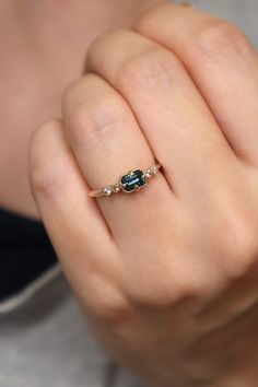 a woman's hand with a ring on it that has an emerald and diamond set in the middle