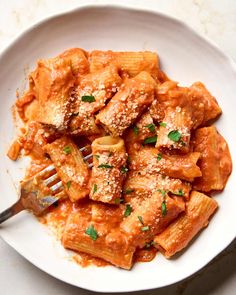 a white plate topped with pasta covered in sauce and parmesan cheese