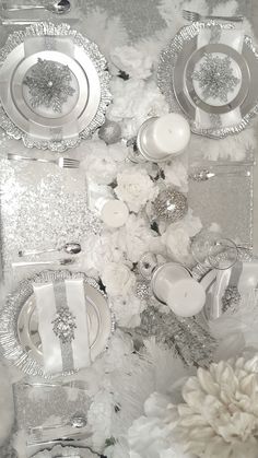 the table is set with white flowers and silver plates