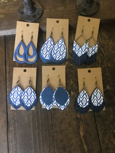 six pairs of blue and white earrings are displayed in front of a brown card board