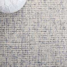 an area rug with white and blue colors on the floor next to a round pillow