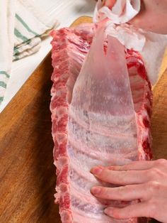 a person is wrapping up a piece of meat on a cutting board