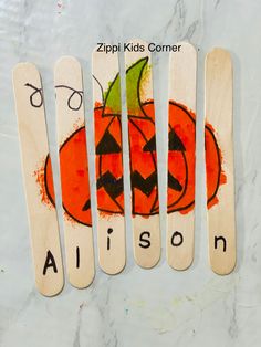 four wooden spoons with painted pumpkin faces and the words alison written on them