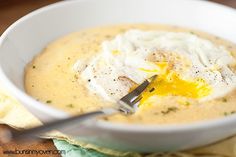 a white bowl filled with soup on top of a table next to a yellow napkin