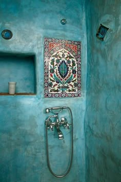 a bathroom with blue walls and a colorful tile design on the wall above the faucet