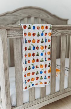 a baby crib with an orange and blue blanket hanging from it's side