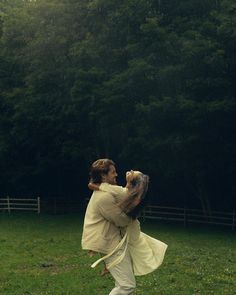 a man carrying a woman on his back in a field with trees in the background