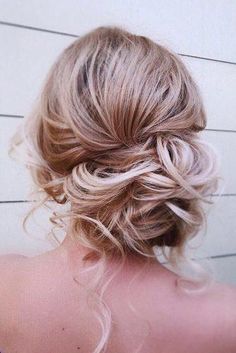 the back of a woman's head, with blonde hair styled into a low bun