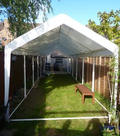 a large white tent sitting on top of a lush green field next to a wooden bench