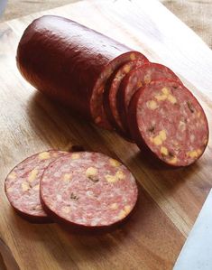 sliced up sausage on a cutting board next to a knife