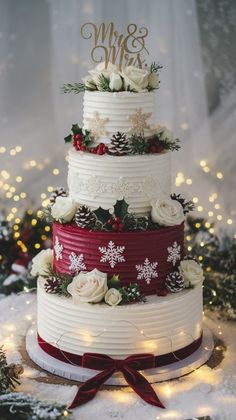 a three tiered wedding cake decorated with white flowers and greenery, topped with red ribbon