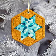 an ornament hanging from a christmas tree decorated with blue and orange geometric shapes