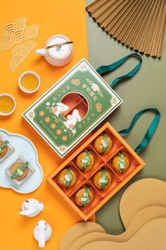 an assortment of chinese desserts and tea on a table with paper fans in the background