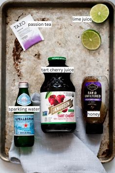 ingredients to make an apple cider recipe laid out on a baking sheet, including tart cherry juice, sparkling water, lemonade and taco