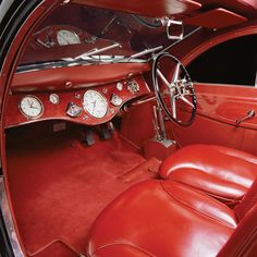 the interior of an old car with red leather seats and gauges on the dashboard