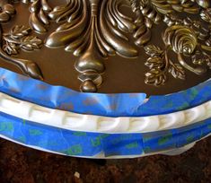 the cake is decorated with blue and white ribbons on it's sides, along with gold leafy designs