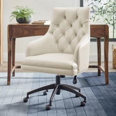 a white office chair sitting on top of a wooden floor next to a desk with a potted plant