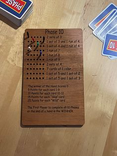 a wooden board game with instructions for playing the card game phase 10, on a wood table