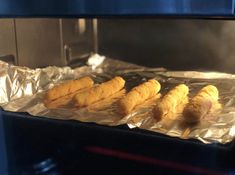 four pieces of bread sitting on top of foil in an oven, ready to be cooked