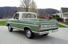 an old green truck parked in front of a house