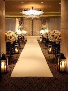 the aisle is lined with white flowers and lit candles for an elegant ceremony at night