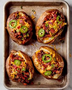 four loaded baked potatoes on a baking sheet