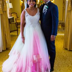 a man and woman standing next to each other in front of a mirror wearing wedding gowns