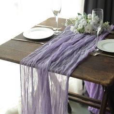 the table is set with plates, silverware and purple linens for an elegant look