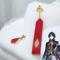 an anime keychain is sitting on top of a white blanket next to a red object