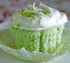 a green cupcake with white frosting and sprinkles