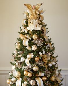 a christmas tree decorated with gold and white ornaments, angel ornament on top