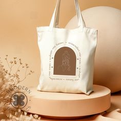 a white bag sitting on top of a table next to a vase with flowers in it