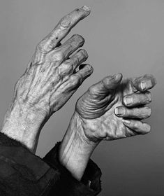 an old man's hands reaching up into the air to catch something with his fingers