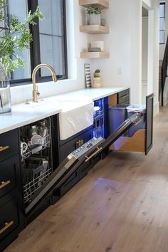 an open dishwasher sitting on top of a wooden floor