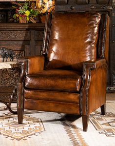 a brown leather chair sitting in front of a fireplace