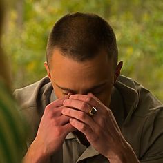 a man covers his face with his hands as he looks at another man's hand