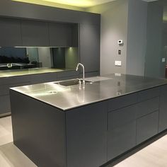 a large kitchen with stainless steel counter tops and cabinets in the background is an empty living room