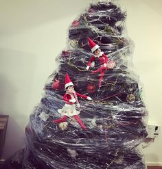 two elfs are sitting on top of a christmas tree made out of plastic wrap