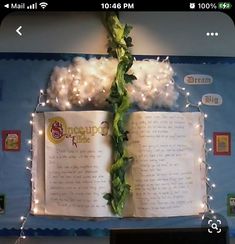 an open book with lights on it hanging from the ceiling in front of a bulletin board