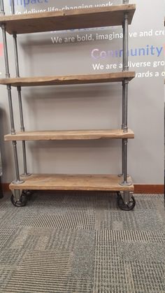 three wooden shelves sitting on wheels in front of a wall