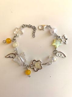 a bracelet with charms and beads on a white surface, including an angel charm in the center