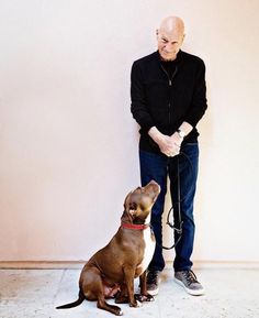 a man standing next to a brown dog with a leash on it's neck