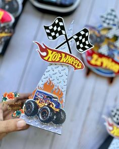 a person holding up a sticker that says hot wheels with flames and checkered flags on it