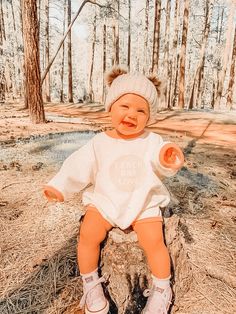 a baby doll sitting on top of a tree stump in the middle of a forest