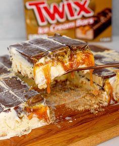 two pieces of cake sitting on top of a wooden cutting board next to a box of twix