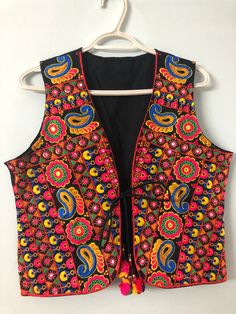 This is a beautiful Indian colorful vest. It is primarily full of pink, yellow and blue embroidery on a black base in the flower and ambi designs throughout the vest. This is a lovely piece to wear on top of traditional Indian clothing or a regular T-shirt to add a dash of color to your outfit. This is a handmade piece, so there may be slight imperfections throughout this piece. Please keep this piece away from water or harsh chemicals to preserve it's long life.  The last image shows the measur Bohemian Black Embroidered Vest, Bohemian Sleeveless Vest With Floral Embroidery, Sleeveless Bohemian Vest With Floral Embroidery, Black Floral Embroidery Sleeveless Vest, Embroidered Multicolor Spring Vest, Multicolor Embroidered Vest For Spring, Spring Embroidered Multicolor Vest, Bohemian Embroidered Sleeveless Vest, Spring Multicolor Embroidered Vest