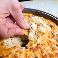 a hand picking up a piece of food from a pan